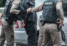 Police arresting a person by a car.