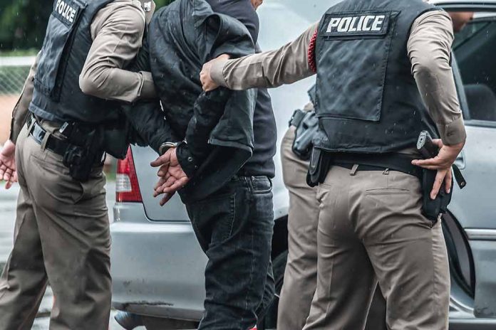 Police arresting a person by a car.