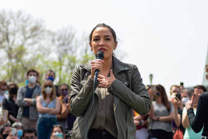 Woman speaking into a microphone outdoors, crowd behind.