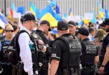 Police officers gathered near a crowd with flags.