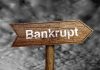 "Bankrupt" sign against cloudy sky background.