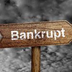 "Bankrupt" sign against cloudy sky background.