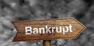 "Bankrupt" sign against cloudy sky background.