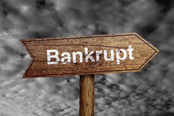 "Bankrupt" sign against cloudy sky background.