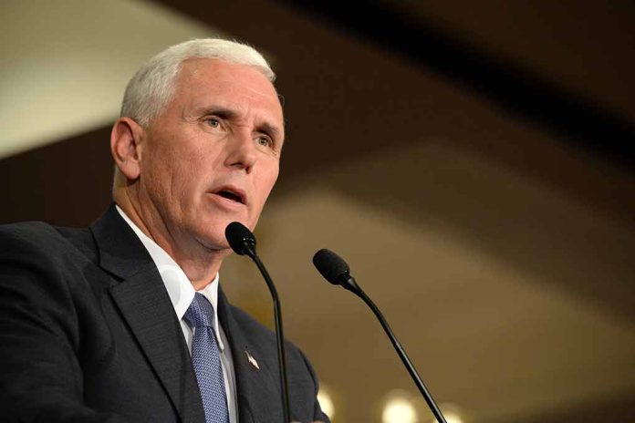 Man in suit speaking at podium with two microphones.