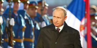 A man in dark coat at a military event.