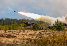 Military tank firing a missile in forest area.