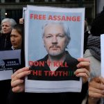 Protesters holding signs supporting Julian Assange.