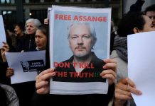 Protesters holding signs supporting Julian Assange.