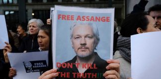 Protesters holding signs supporting Julian Assange.