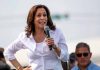 Woman speaking into microphone at outdoor event.