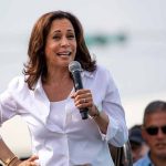 Woman speaking into microphone at outdoor event.