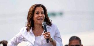 Woman speaking into microphone at outdoor event.