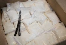 Bags of white powder with scissors in cardboard box.