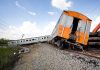 Tilted train derailed off tracks in rural area.