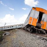 Tilted train derailed off tracks in rural area.