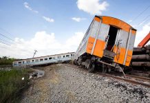 Tilted train derailed off tracks in rural area.