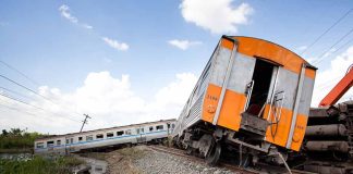 Tilted train derailed off tracks in rural area.