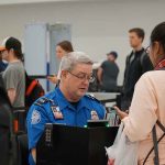 TSA agent checks passenger's documents at airport security.