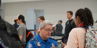 TSA agent checks passenger's documents at airport security.