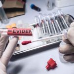 Gloved hands holding evidence tube and cotton swab.