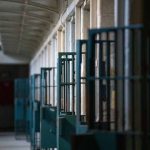 Prison cell block corridor with gated doors.