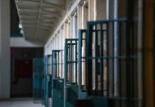 Prison cell block corridor with gated doors.