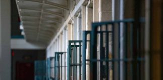 Prison cell block corridor with gated doors.