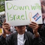 Person holding "Down with Israel" sign at protest.