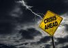 Yellow "Crisis Ahead" sign with stormy sky.