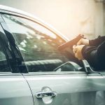 Person pointing gun at car window