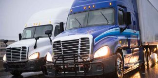 Two trucks driving on a wet road.