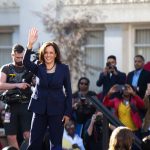 Woman in blue suit waving to a crowd.