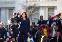 Woman in blue suit waving to a crowd.