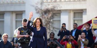 Woman in blue suit waving to a crowd.