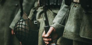 Soldiers in uniform holding rifles and grenades.