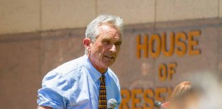 Man speaking into microphone outside government building.