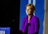 Woman in purple jacket speaking at podium.