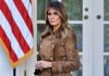 Woman in brown coat with American flag background.