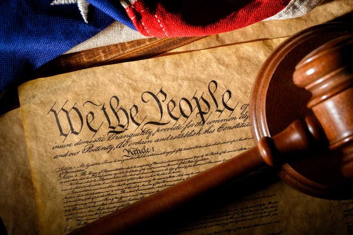 Gavel on U.S. Constitution with flag backdrop.