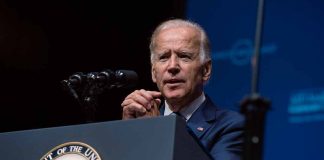 Man speaking at a podium with microphones.