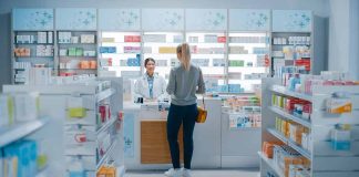 Customer talking to pharmacist at a bright pharmacy.