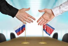 Two hands near flags of Russia and North Korea.