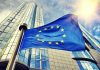 European Union flag waving in front of skyscraper.