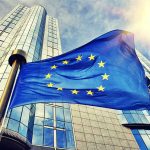 European Union flag waving in front of skyscraper.