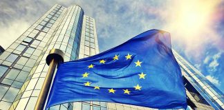 European Union flag waving in front of skyscraper.