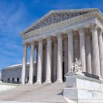 Supreme Court building with columns and statues.