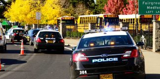 Police cars and school buses on a road.