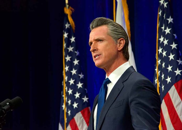 Man in suit speaking, flanked by American flags.