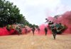 Soldiers running from armored vehicles with red smoke